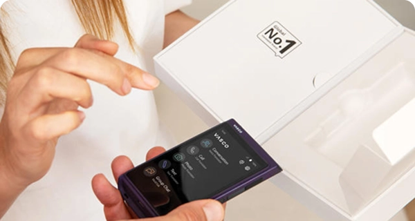 Um grande plano de uma pessoa a retirar um Vasco Translator Q1 roxo da sua caixa de venda ao público branca.