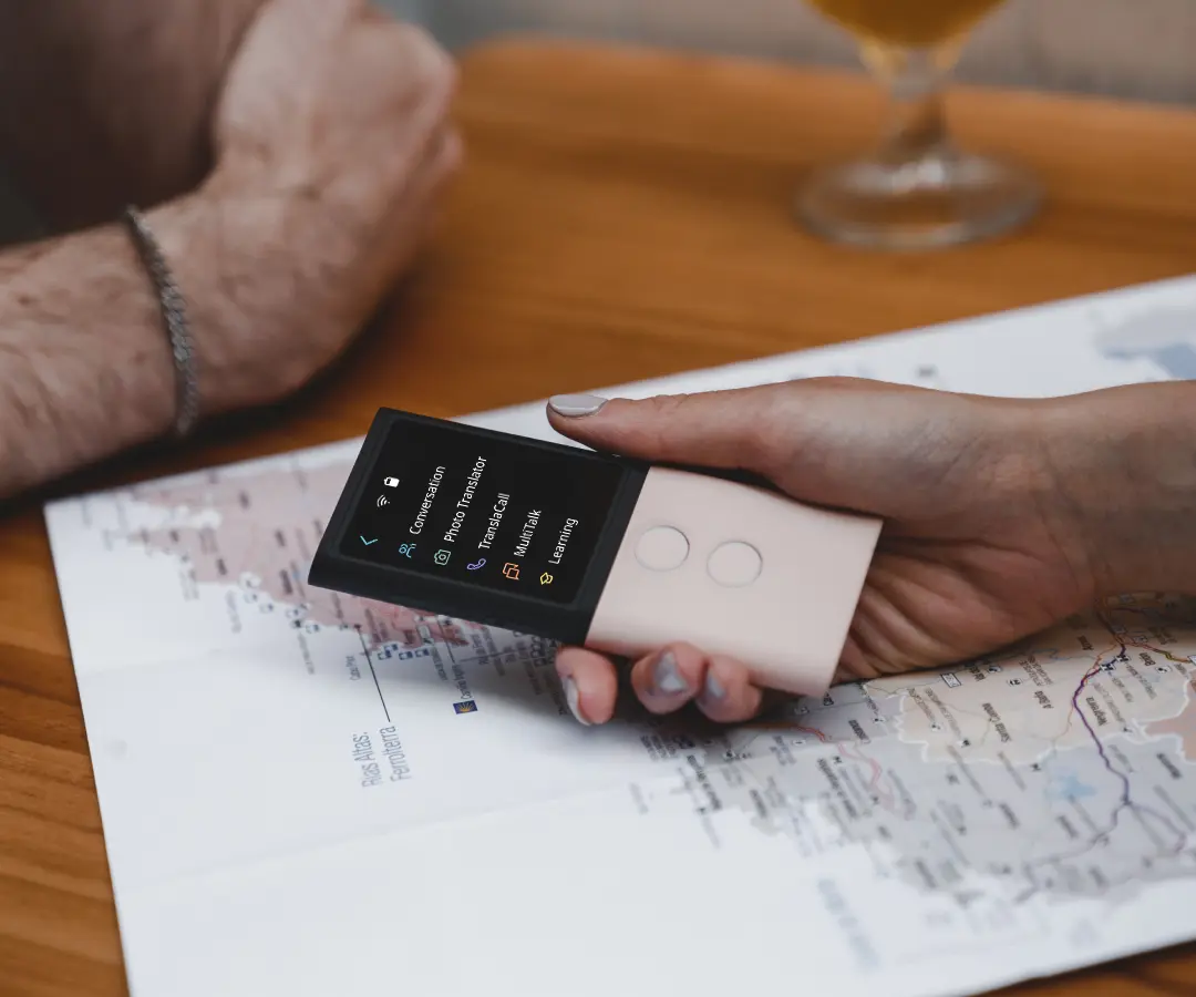 Close-up de uma mão segurando um tradutor sobre uma mesa com um mapa